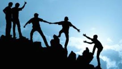 silhouettes of people helping each other climb a rocky mountain in a teamwork scene